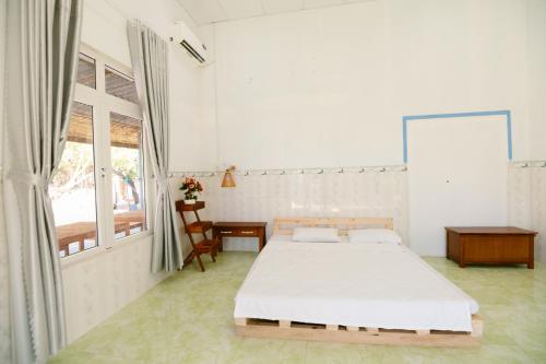 a white bedroom with a bed and a window at Om Homestay in Tuy An