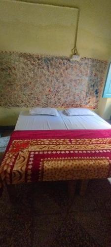 een slaapkamer met een bed met een deken erop bij Sri Viswanatham guest House in Varanasi