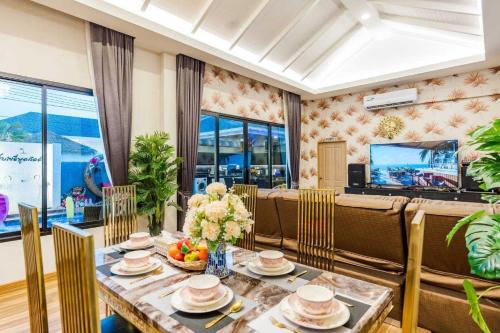 a dining room with a table and chairs and a television at Sabaidee Pool Villa Cha-am in Cha Am