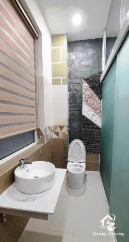 a bathroom with a white toilet and a sink at Friendly Homestay in Kon Tum