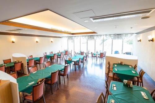 una sala da pranzo con tavoli e sedie verdi di Kyukamura Fuji a Fujinomiya