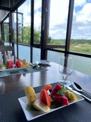 a plate of fruit on a table with a wine glass at Blue Wild - Yala - Plastic Free & Sustainable in Tissamaharama