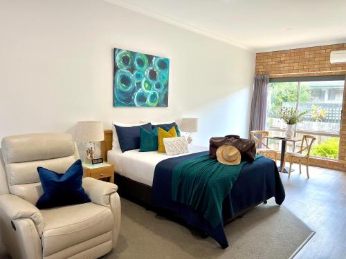 een slaapkamer met een bed en een stoel bij Coastal Waters Motor Inn in Lakes Entrance