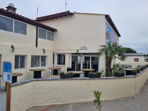 a building with tables in front of it at MOBILHOME SOLEIA NEUF 2023 MAR ESTANG SIBLU VILLAGE Canet-en-Roussillon in Canet-en-Roussillon
