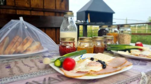 a table with plates of food and jars of sauce at Glamping Livada cu lavanda 