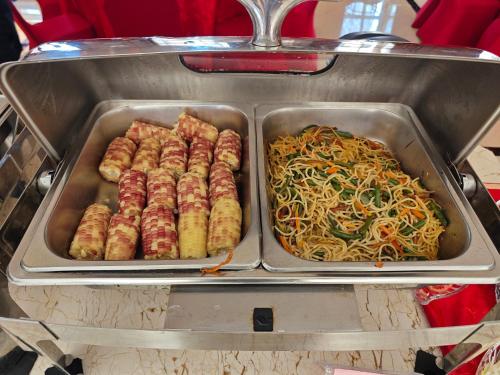 two trays of food with noodles and sausages at Golden Peacock Hotel Blantyre in Blantyre