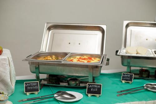 two trays of food on a table with plates and spoons at Eldorado Rustic Hotel in Nakuru