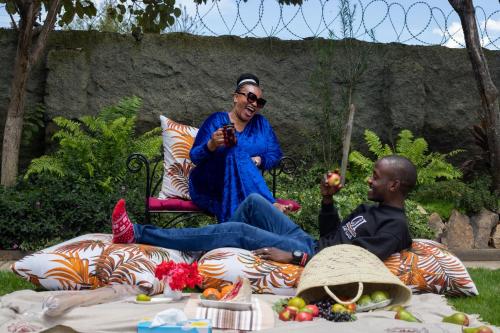 two people sitting on a bench in the grass at Eldorado Rustic Hotel in Nakuru