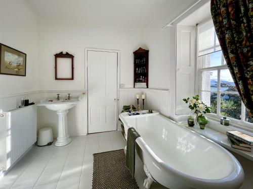 Baño blanco con bañera y lavamanos en Applecross Manse en Applecross