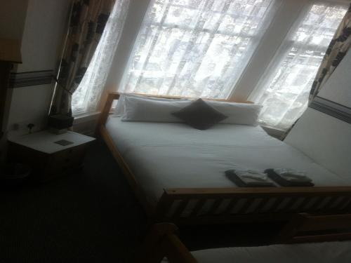a bed in a room with a window with shoes on it at Deneside Guest House in Blackpool