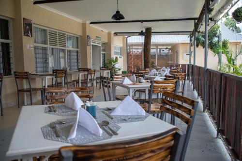 a restaurant with white tables and chairs and a fence at Eldorado Rustic Hotel in Nakuru