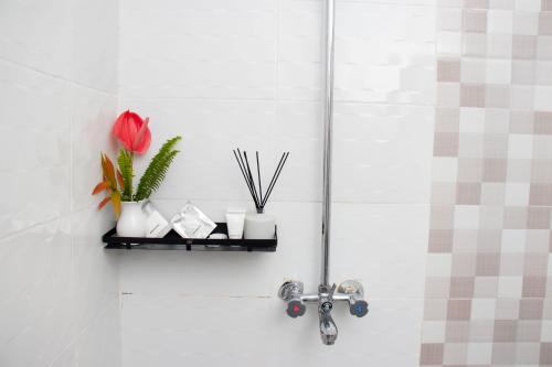 a bathroom with a shower with a flower on a shelf at Eldorado Rustic Hotel in Nakuru