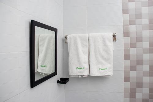 ein Badezimmer mit weißen Handtüchern und einem Spiegel in der Unterkunft Eldorado Rustic Hotel in Nakuru