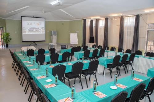 a conference room with blue tables and chairs and a screen at Eldorado Rustic Hotel in Nakuru