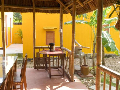 um pátio com uma mesa e cadeiras e uma casa amarela em Mango House Retreat Quy Nhon em Quy Nhon