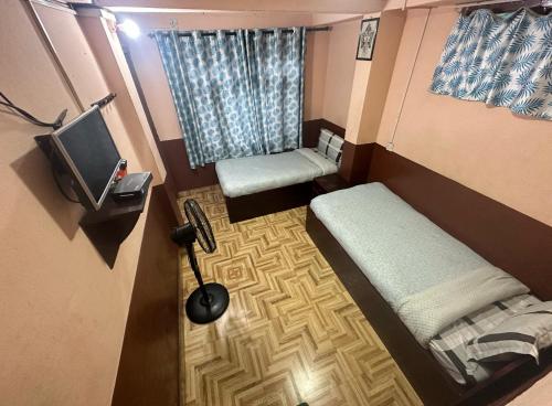 a small room with two beds and a television at Nirvaan Guest House (Hotel Bibidh) in Kathmandu