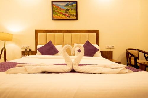 a hotel room with a bed with towel animals on it at Perfectstayz Value Hills near Laxman Jhula in Rishīkesh
