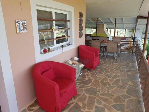 sala de estar con 2 sillas rojas y cocina en Farma Tsalta Olympus Larisa, en Pyrgetós