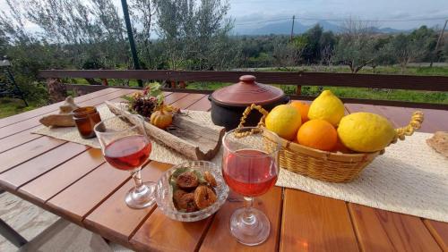 a table with two glasses of wine and a basket of fruit at homonatura petrinum in Ariokhórion