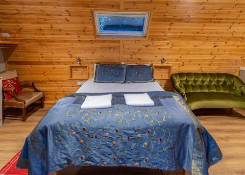 a bedroom with a blue bed and a green couch at Missing Link Glamping in East Grinstead