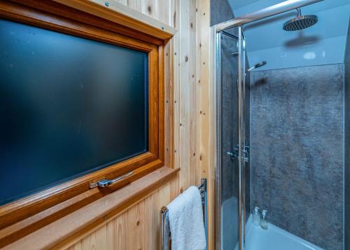 a large television in a bathroom with a shower at Missing Link Glamping in East Grinstead