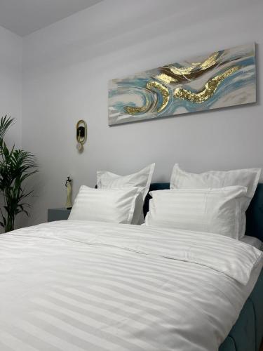 a white bed with white pillows and a painting on the wall at Style Central in Bucharest