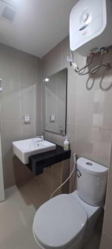 a bathroom with a white toilet and a sink at Apartemen Nuvasa Bay in Nongsa