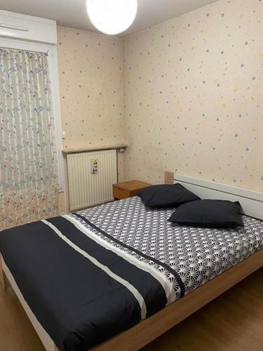 um quarto com uma cama com lençóis brancos e pretos em Appartement spacieux Gentilly em Gentilly