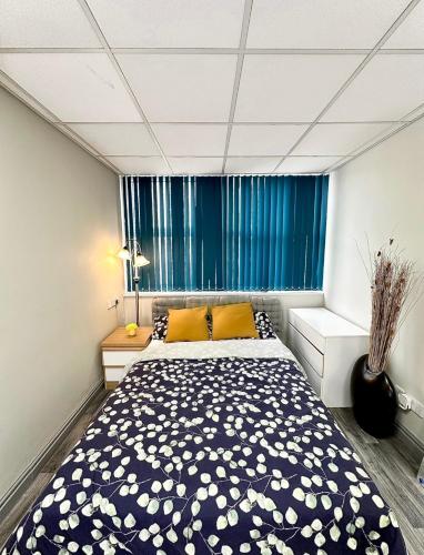 a bedroom with a large bed with blue curtains at Papaya’s en-suite in Hoyland Nether