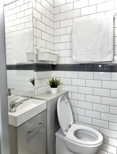 a white bathroom with a toilet and a sink at Papaya’s en-suite in Hoyland Nether