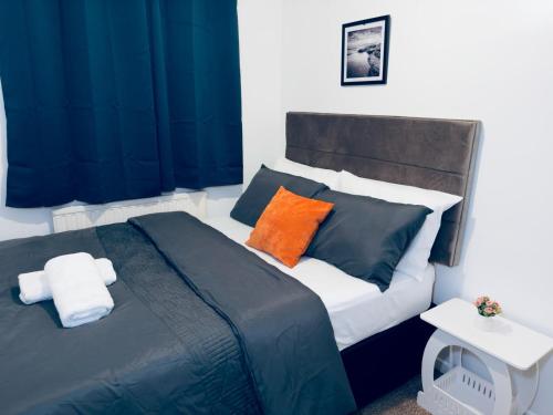 1 dormitorio con 1 cama con almohadas azules y naranjas en Home Paradise Manchester- 3 Bedroom House en Mánchester