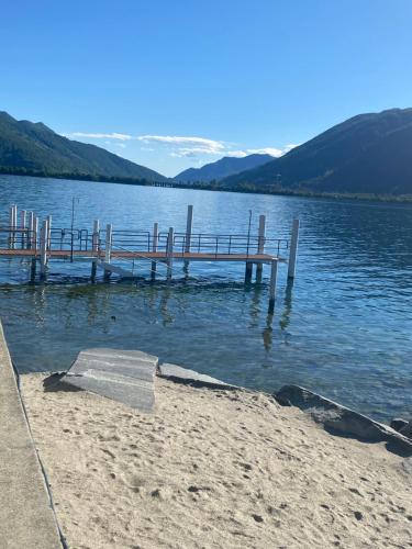 a dock on a lake with mountains in the background at Apartment Bella Vista Lugano in Bissone