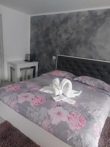 a bed with pink flowers and a butterfly on it at Cazare Moldi Btt in Câmpulung Moldovenesc