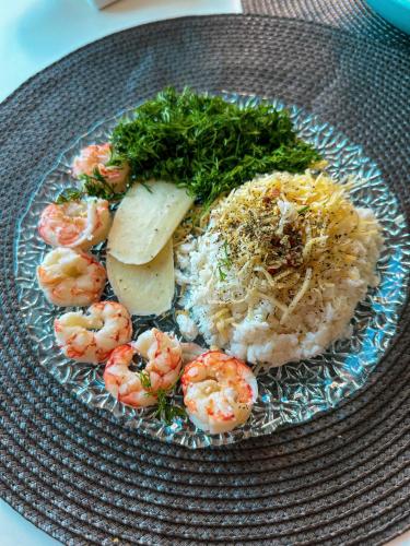 a plate of shrimp and rice with cheese and herbs at Batumi High View in Batumi