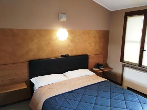a bedroom with a bed and a light on the wall at Hotel Motel Est in Peschiera Borromeo