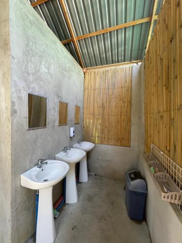 a bathroom with two sinks and a trash can at Russell Place Tent in Port Barton