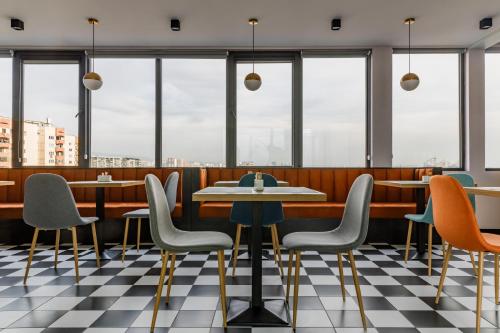 a restaurant with tables and chairs and windows at Address Inn in Tbilisi City