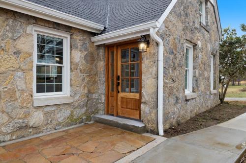 uma casa de pedra com uma porta de madeira e janelas em Tranquil Mountain Escape Luxurious 5-Bedroom Farmhouse with Pool em Maryville