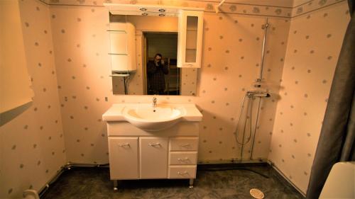 a person taking a picture of a bathroom with a sink at LAKESIDE AURORA CABINS in Kiruna