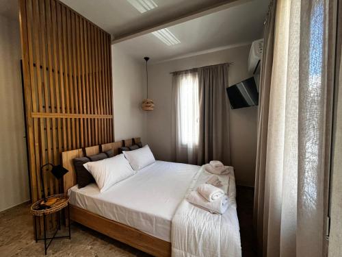 a bedroom with a bed with white sheets and towels at Orfeas Luxury Rooms & Studio in Skopelos Town