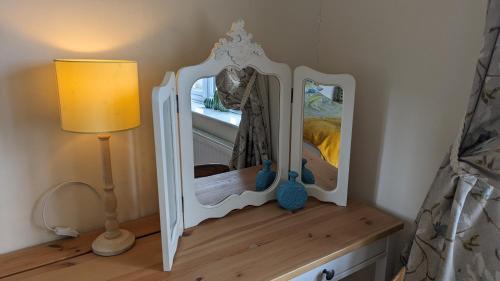 a mirror sitting on a dresser next to a lamp at Cosy family cottage south Somerset in Long Sutton