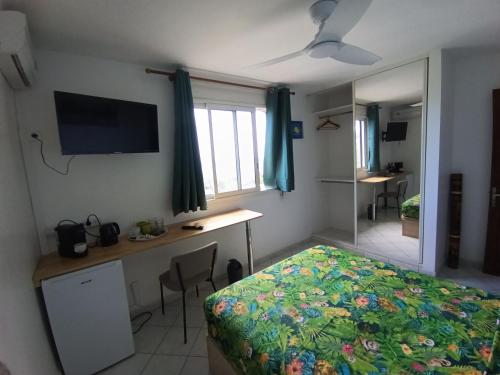 una camera con letto, scrivania e TV di Chambre Vue sur Mer a Saint-Leu