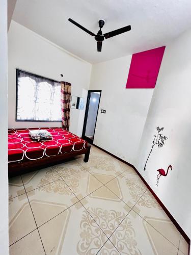 a bedroom with a red bed and a ceiling fan at Lumina Home Stay in Puducherry