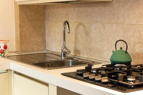 a kitchen with a sink and a stove with a green tea kettle at Nel cuore di Oristano in Oristano