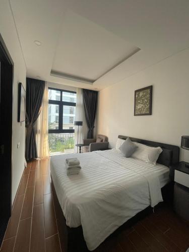 a bedroom with a large white bed and a chair at Le Palmier Phu Quoc Hotel - Free Shuttle To Grand World in Phu Quoc