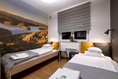 ポランチクにあるVela Polańczyk Rodzinne Domki Nad Jezioremの壁に絵画が飾られた部屋のベッド2台