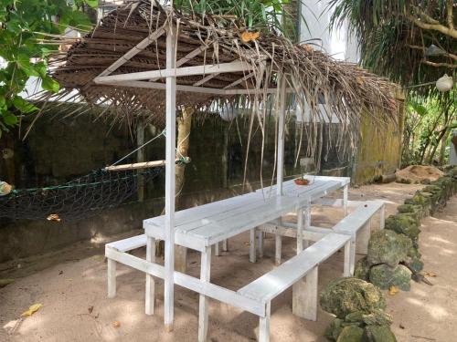 a white picnic table with a bench in a garden at Oruwa Turtle Beach Villa in Kosgoda