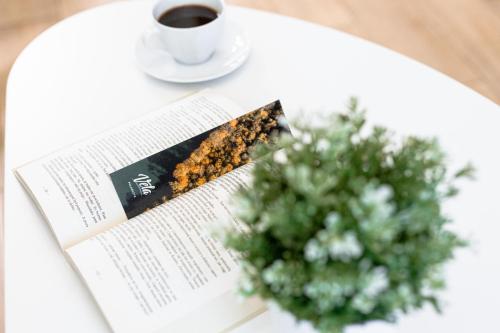 a table with a book and a cup of coffee and a plant at Vela Polańczyk Rodzinne Domki Nad Jeziorem in Polańczyk