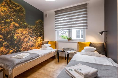 two beds in a room with a painting on the wall at Vela Polańczyk Rodzinne Domki Nad Jeziorem in Polańczyk