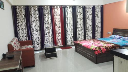 a bedroom with a bed and a table and curtains at Studio Apartment On The Lake in Lavasa
